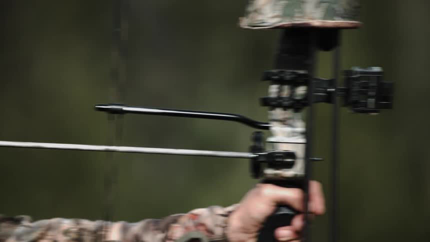 Man wearing camouflage shoots an arrow
