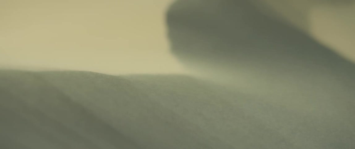 Sand blowing over a large desert dune