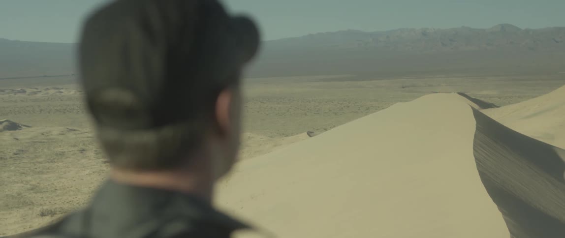 Man stands before a large windy desert