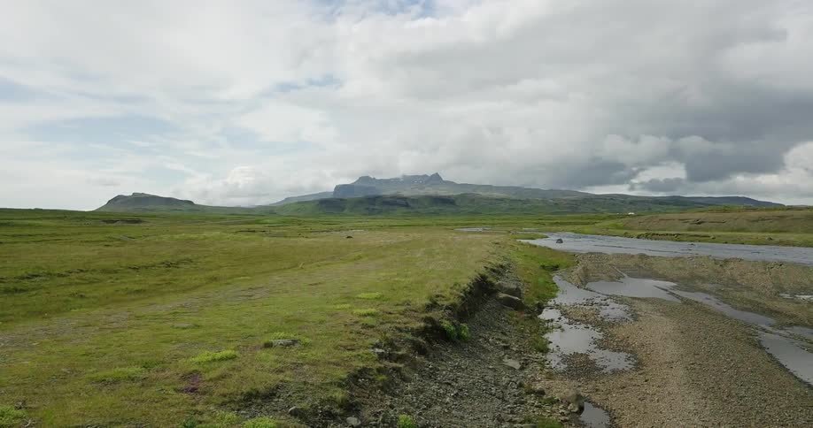 Grey clouds hover over a shallow river bed in a natural setting
