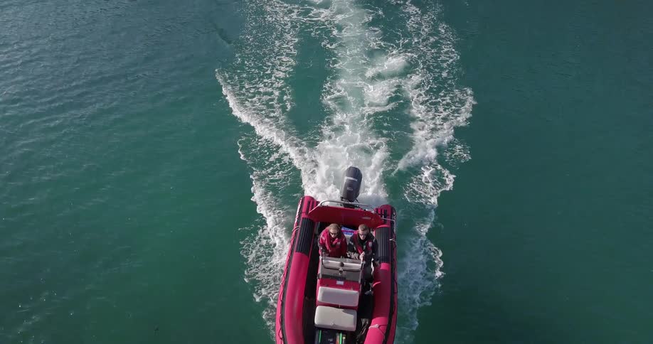 People drive a boat across the water leaving a wake