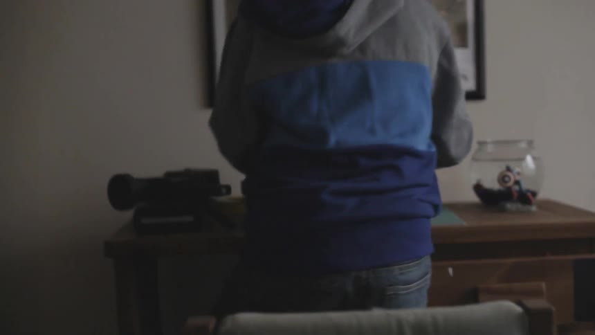 A boy types on a typewriter before rising taking the paper from the typewriter and running down the hallway