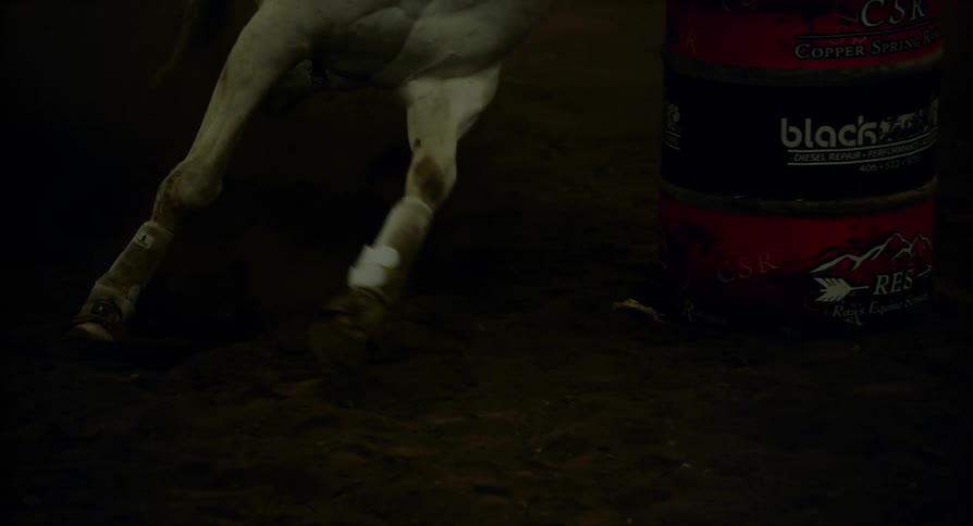 Close up of of a horse's legs as it runs around a barrel