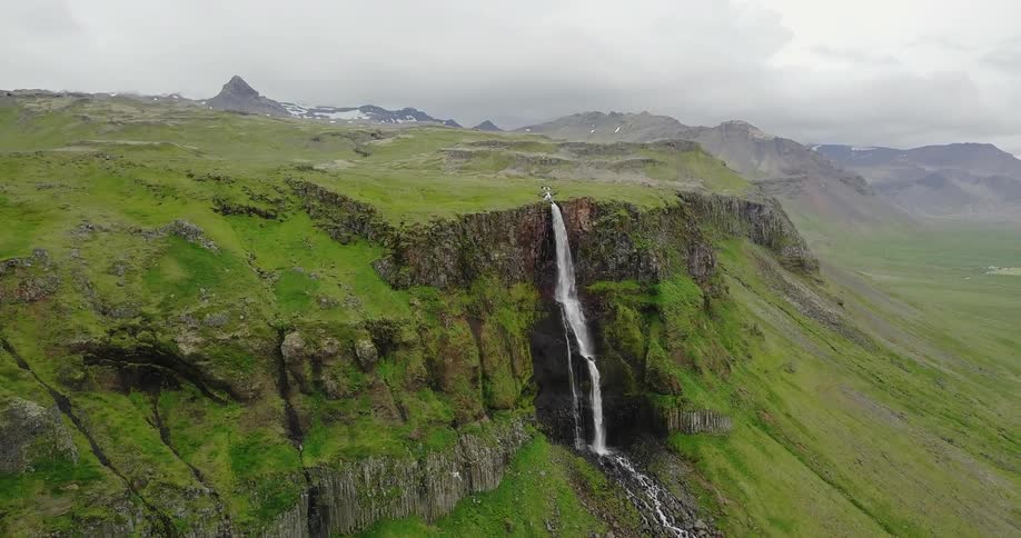 A waterfall cascades over a sheet cliff down into a valley