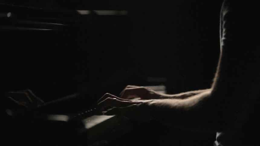 Person playing a piano in a dark area