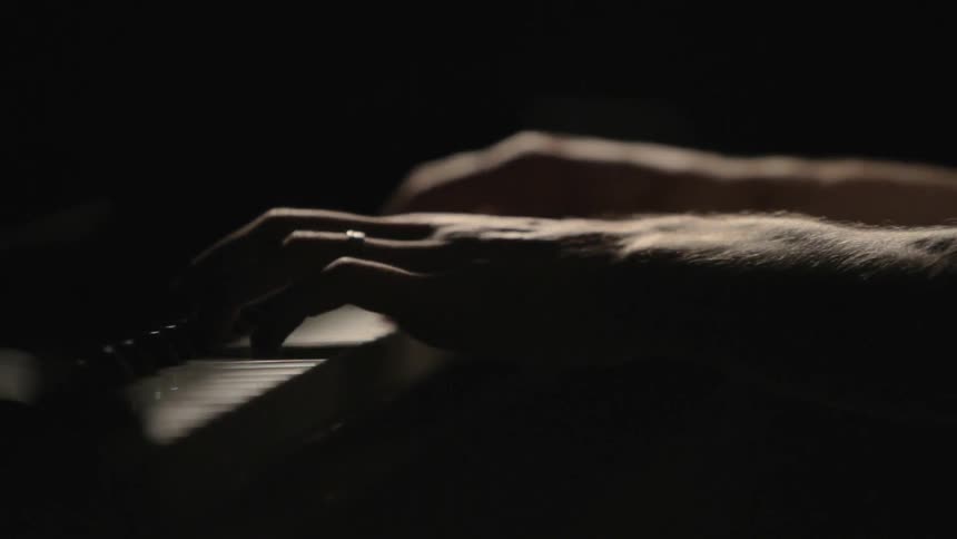 Man playing the piano in a dark room