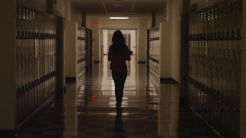 Woman walking down a dark school hall