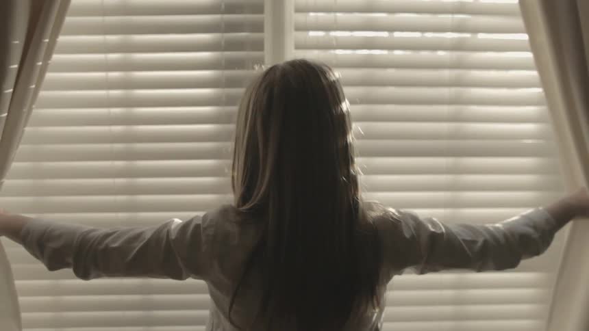 A person opening up curtains