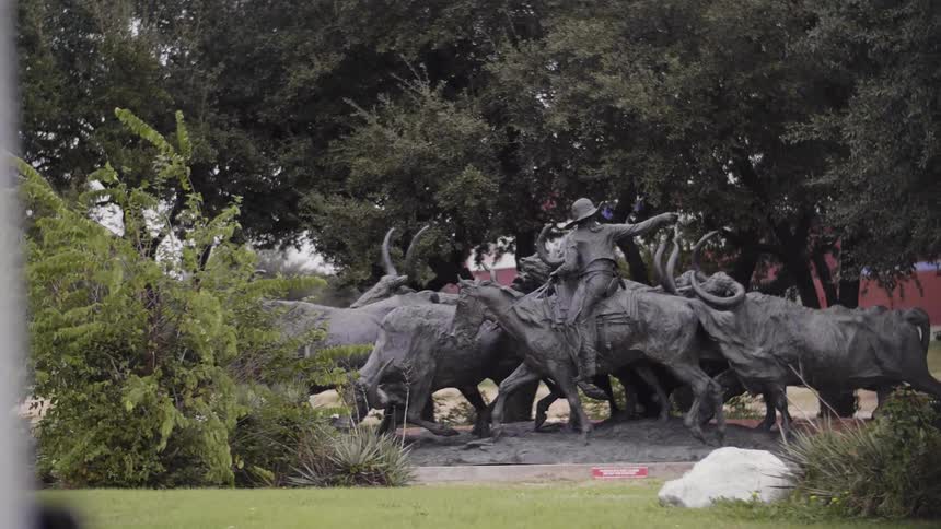 A statue of person riding cattle in the middle of trees