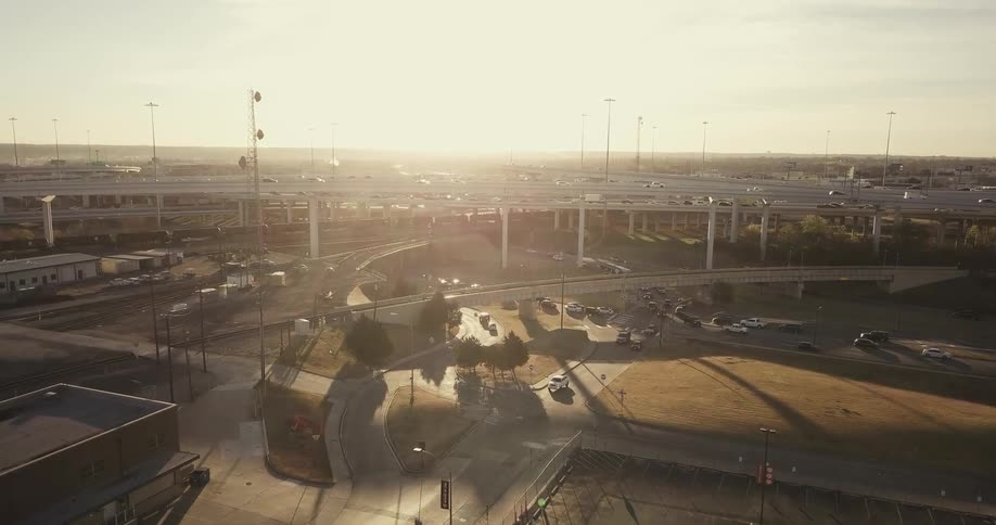 Cars drive on city roads at sunset