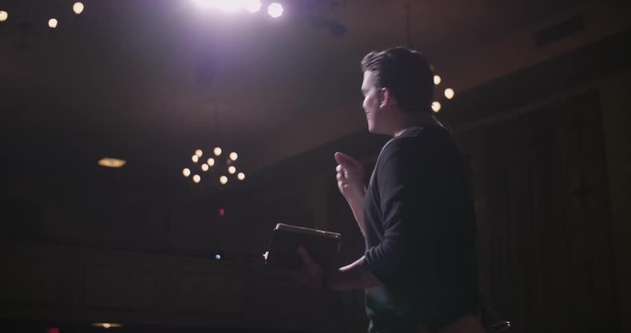 A man is giving a speech reading from a book