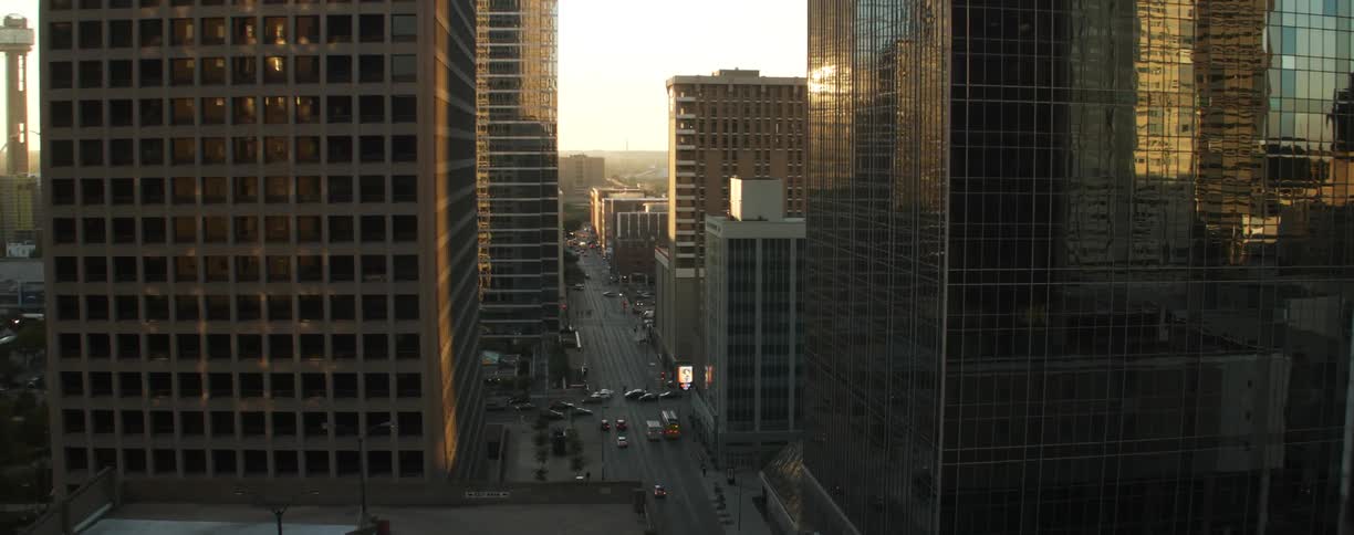 Cars drive on city streets at sunset