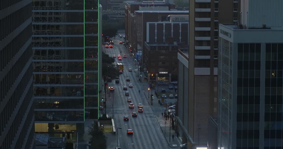 Cars drive on a city street at dusk