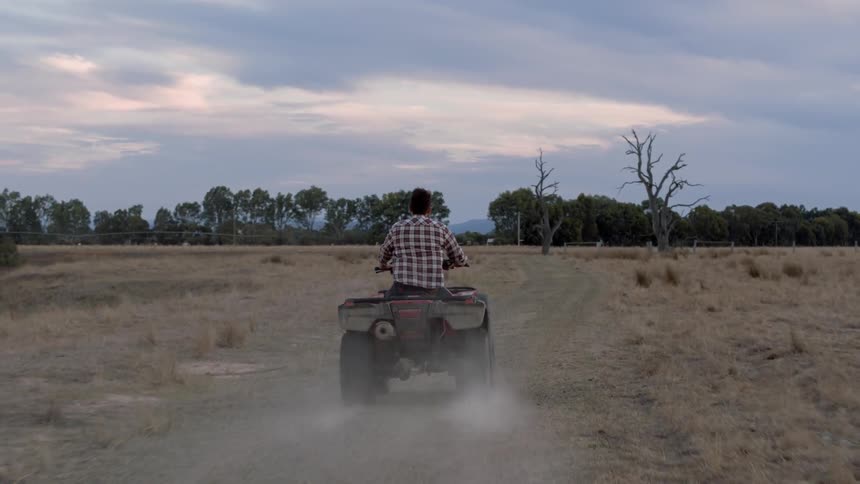Man rides a four wheeler through a field