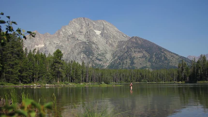 A man stands in a rippling mountain lake