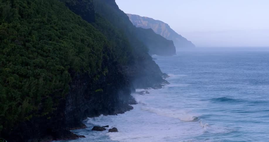 Waves roll onto a forested mountain