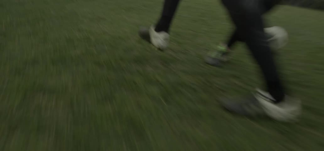 A soccer player passes the ball through another player's legs