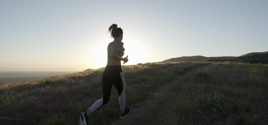 A woman is running uphill at sunset