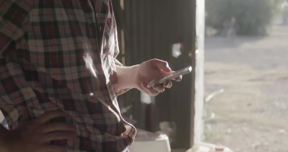 A man is using his phone in a barn