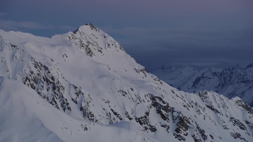 Snow covers a mountain ridge on a cloudy day