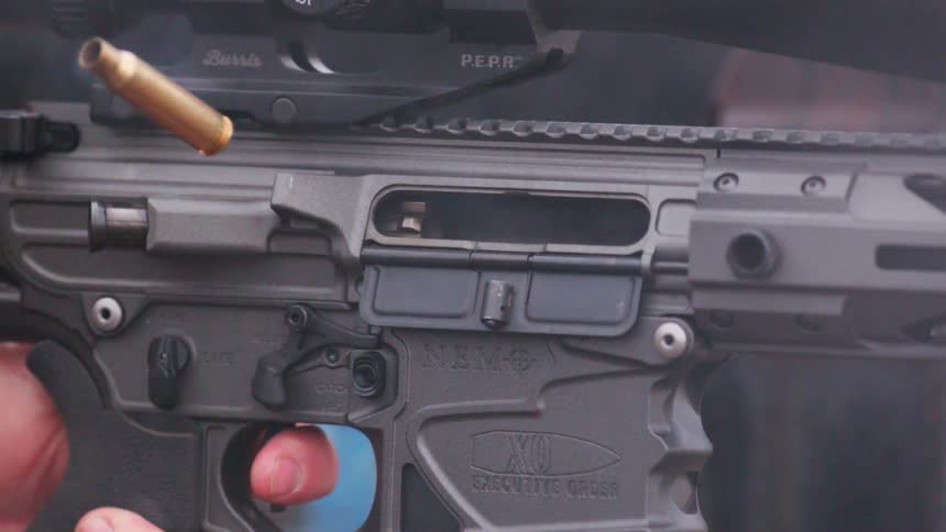 A finger pulls a gun trigger and an empty bullet shell flies out the side
