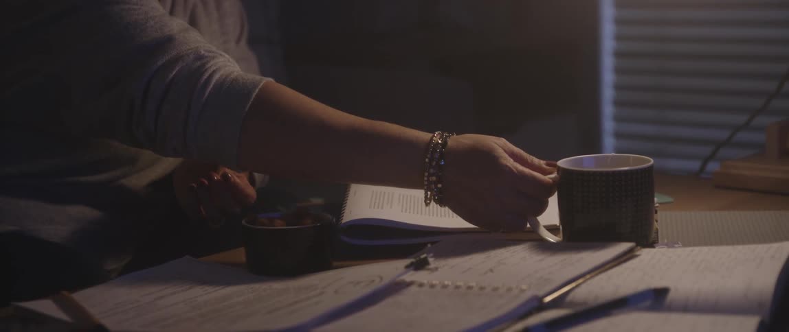 Person sitting at a desk picking up a mug of tea