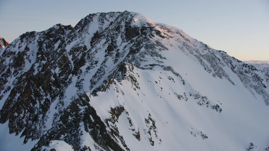 Snow covers a mountain ridge at sunset