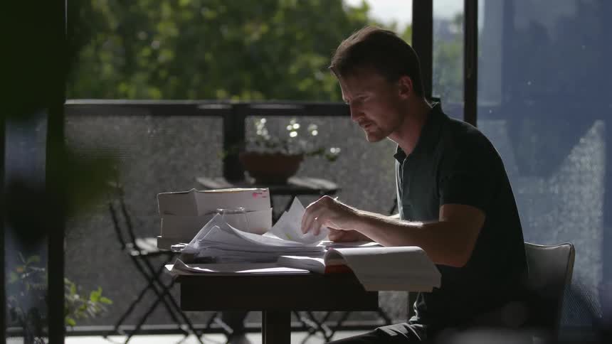 A man does paperwork at a small desk
