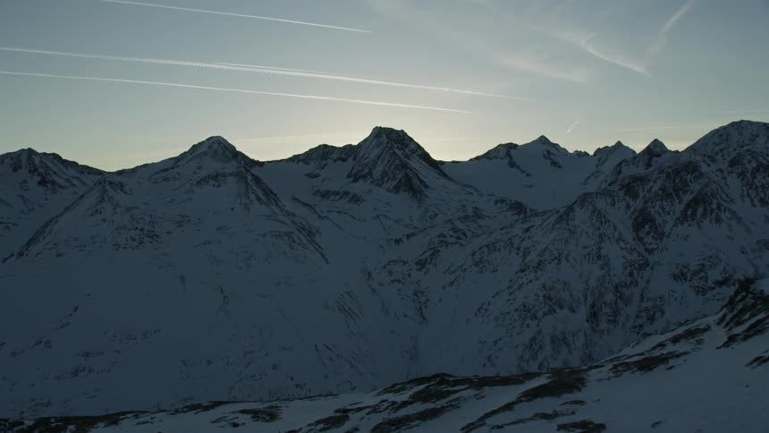 Snowy mountains are shown at sunset