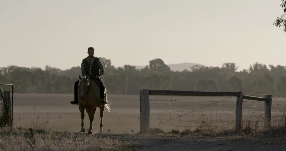 A man rides a horse through a gate
