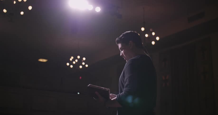 A speaker reads from a book while giving a presentation