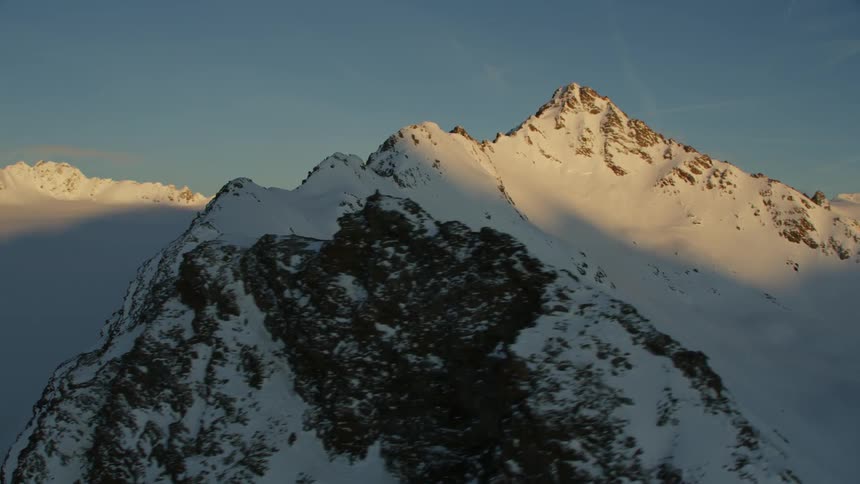 Sunlight shines on a snowy mountain peak