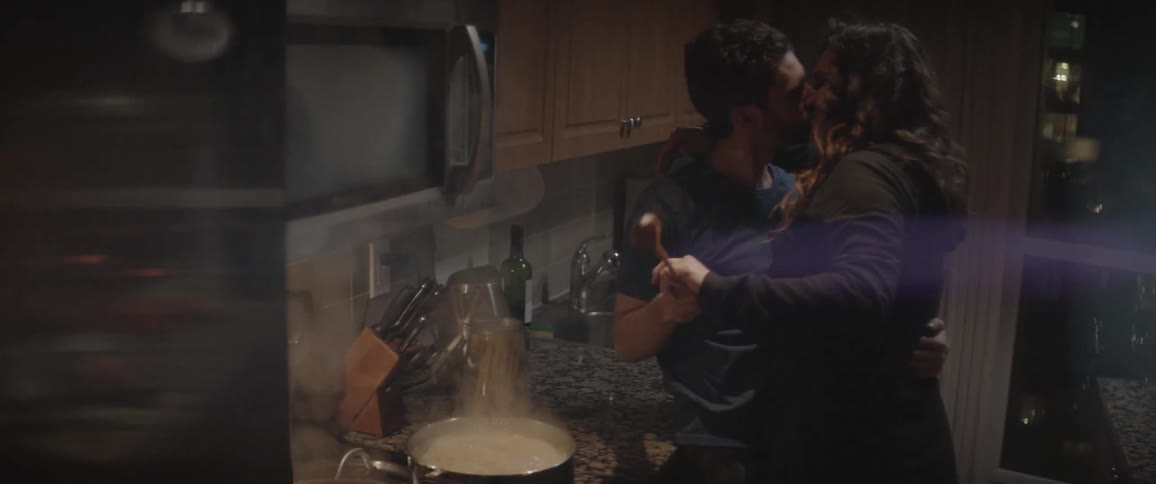 A couple are cooking together and kiss