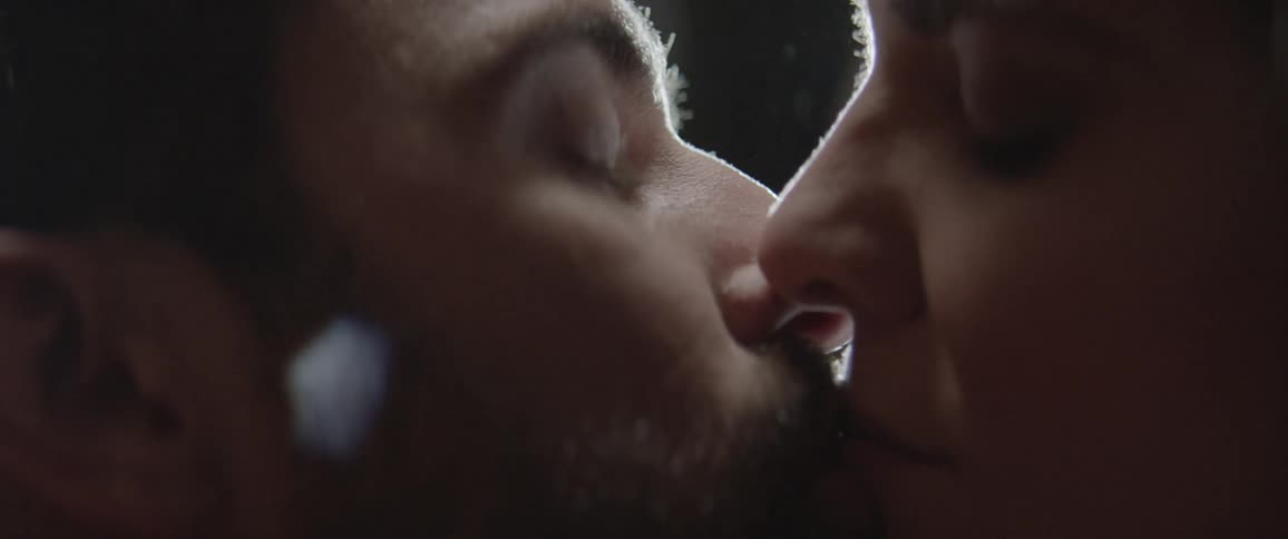 A man and woman kiss under a spotlight