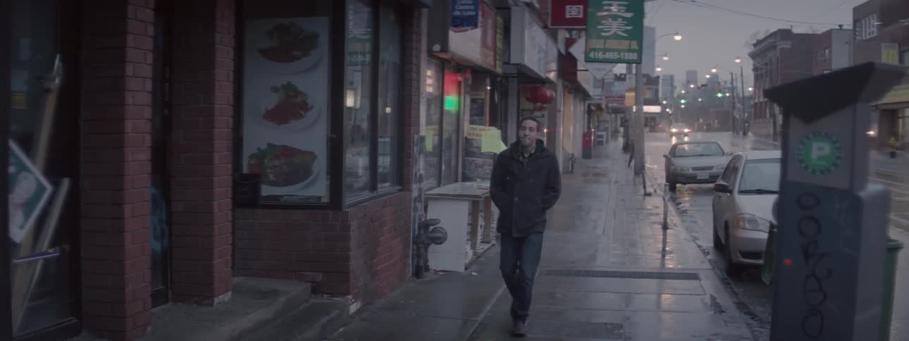 A man walks down a wet sidewalk