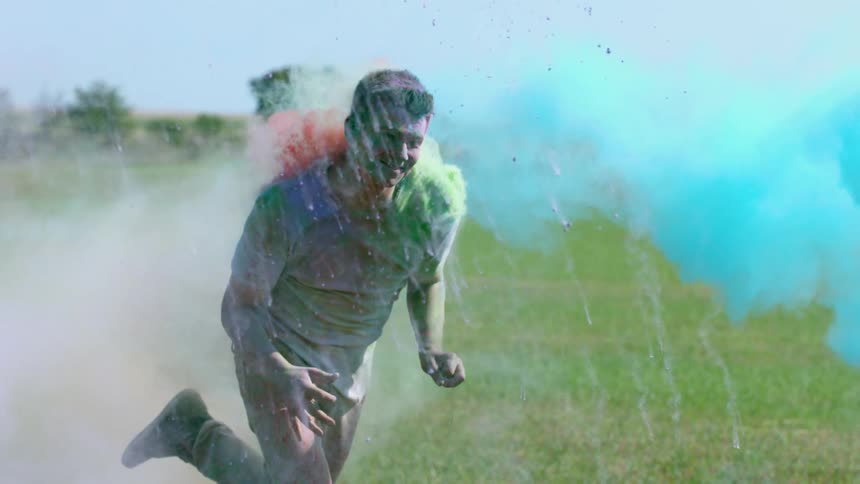 A man runs while colorful powder flies around him