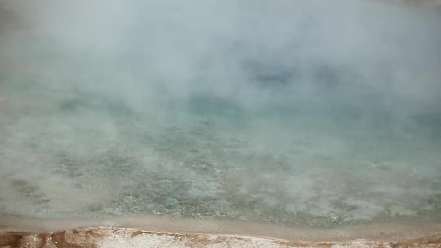 Steam rises from a rippling hot spring