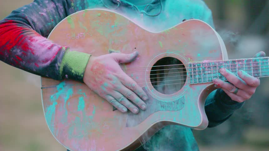 A person and their guitar are covered in colorful powder