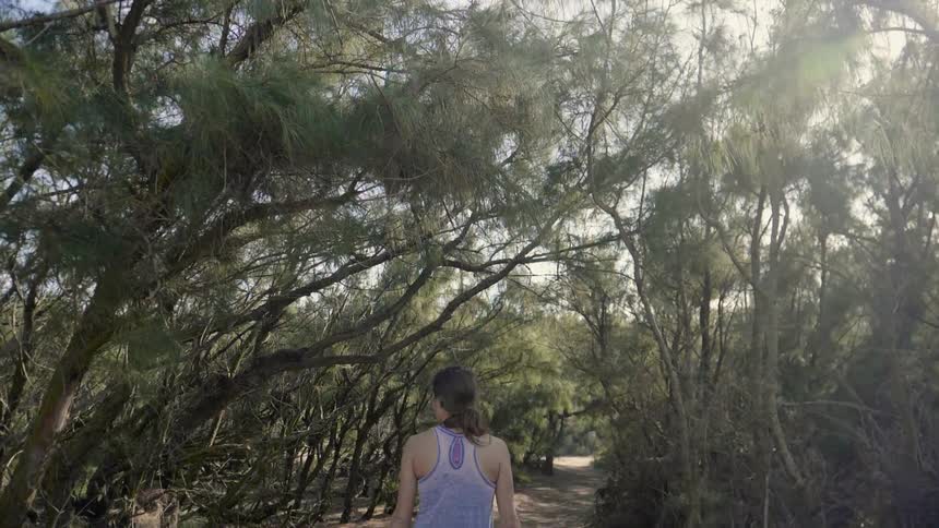 Woman walks down a path in the woods
