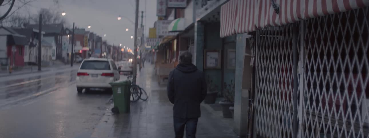 A man walks down a rainy city sidewalk
