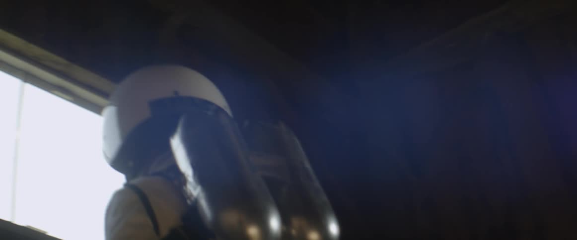 A man in a space outfit jumps over some hay