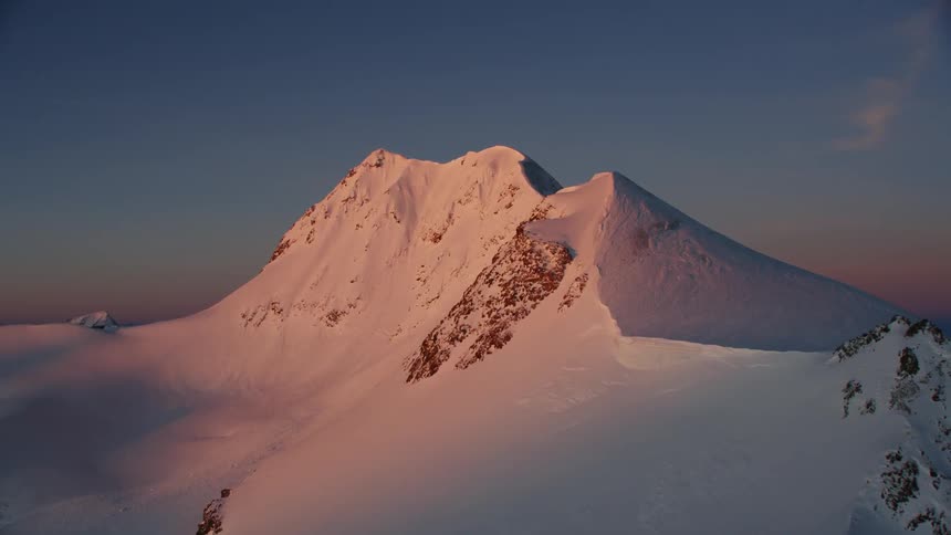 A snow covered mountain at sunset