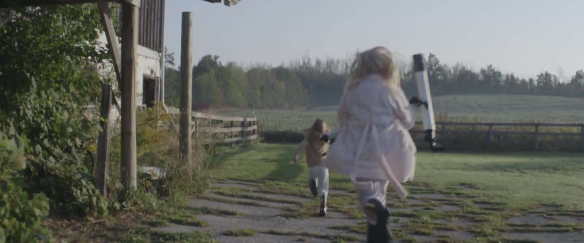 Two girls run across a lawn with a telescope in hand