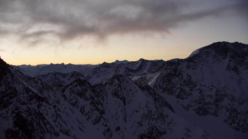 Gray clouds hover over a mountain range at dawn