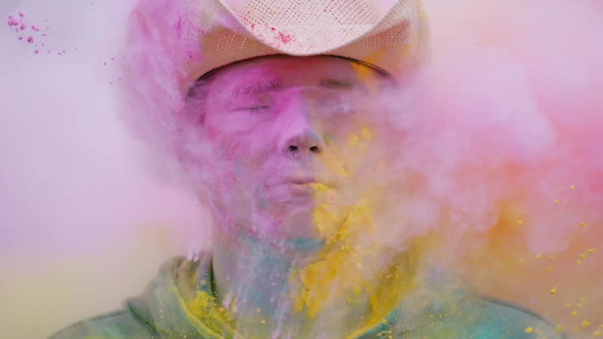 A cowboy's face is covered in colored powder