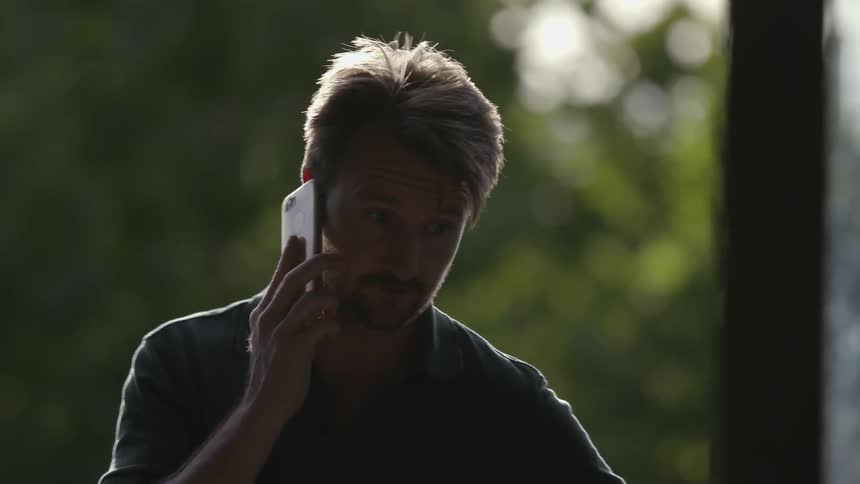 A man with a goatee talks on a phone