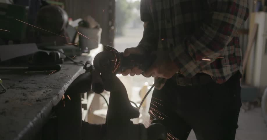 Sparks fly as a man uses a grinder in a workshop