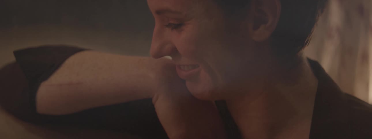 A woman smiles and leans against her arm