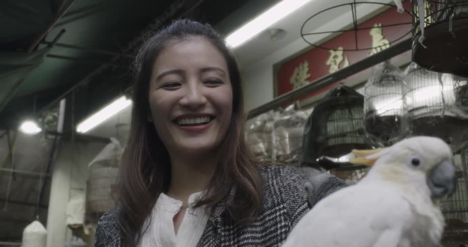 A woman is holding a white bird and laughing