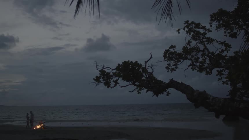 A couple embrace next to a fire on the beach